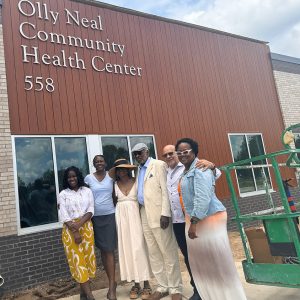 African American family standing before brick and wooden building