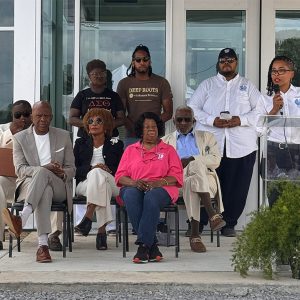 Group of African American men and women seated; African American woman standing at lectern