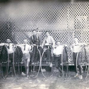 Group of white men with antique bicycles with huge front wheels