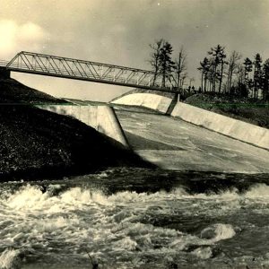 Water flowing over a concrete slope with trees in the background