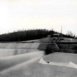 Lake with sloping spillway and a house up on the shore