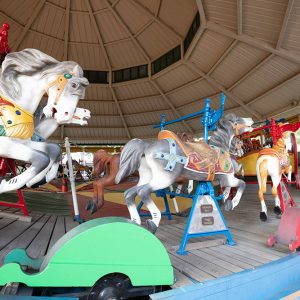 Merry-go-round horses with red and blue poles and a small green cart