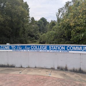 blue sign on wall "welcome to the new College Station community  sponsored by the Progressive League of College Station"