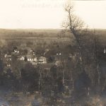 A small town and trees seen from atop a hill