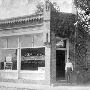 Brick bank building with white man standing in doorway