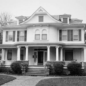 Multistory white wooden house with covered porth with columns