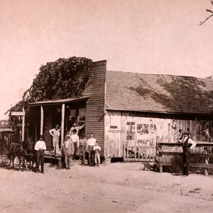 men and a boy standing on the porch of a wooden store building