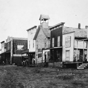 Small town street scene with dirt street and wooden buildings