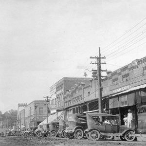 Small town street scene with rows of buildings and cars parked alongside