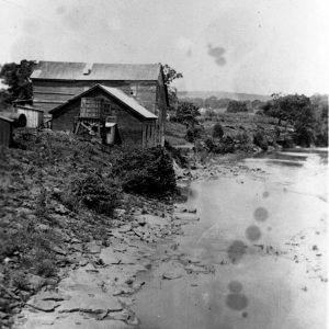 Small wooden mill building on the shore of a creek