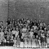 Large group of white children posing in a class photo with some teachers