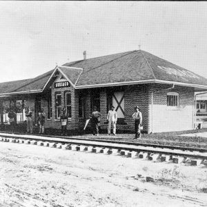 Single story brick depot building with men standing in front