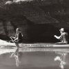 two men in a canoe in live jackets and hats rowing a canoe that says "Withrow Springs State Park" on the side