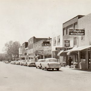 Cars parked along small town business district composed of multistory storefront buildings