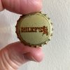 Fingers holding a bottle cap "Riley's"