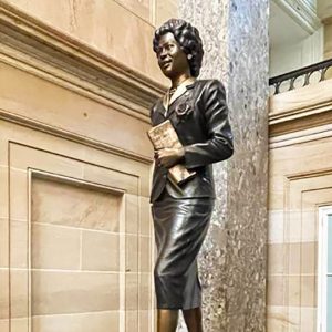 Bronze statue of woman wearing a business suit and holding a folded newspaper