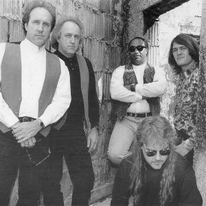 Four white men and one African American man posed next to concrete walls