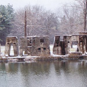 Concrete blocks in varying shapes and sizes standing in snow covered foundation next to body of water