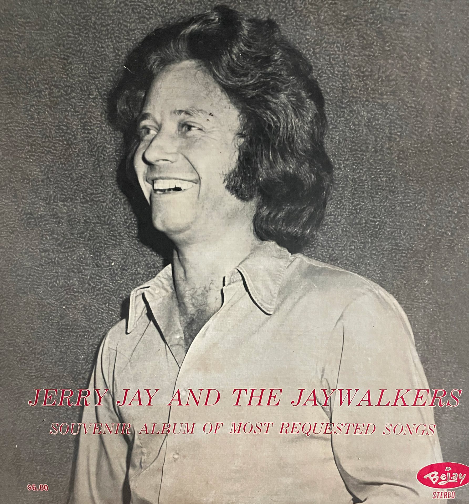 White man with shoulder length hair in button up smiling looking off camera text "souvenir album of most requested songs"