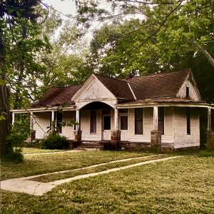 Single story wooden building with stone accents holding up seven wooden pillars around front of house