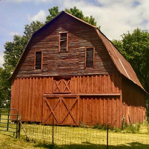 Large wooden barn behind chicken wire fence