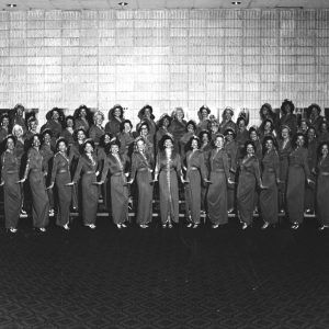 Large group of women arms out by their sides posed in rows on standing risers