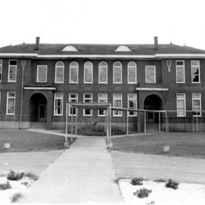Sidewalk leading to two story brick building with covered walkway