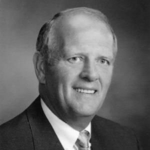 Middle aged white man dressed in suit and tie smiling
