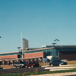 Multistory brick building with large glass panels behind parking lot