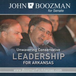 Middle aged white man clean shaven wearing glasses sitting with other white men speaking into microphone text "Unwavering Conservative Leadership for Arkansas"