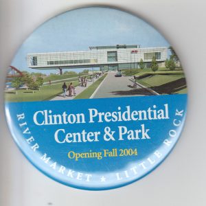 Round button text "Clinton Presidential Center and Park Opening Fall 2004 River Market Little Rock" under illustration of people walking on sidewalks next to large lawn leading up to three story glass and steel building