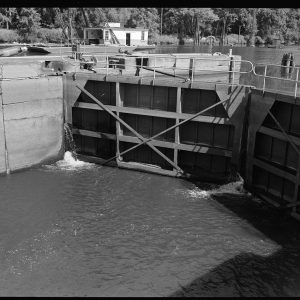 Large steel barrier in river gates closed separating two bodies of water one higher than the other