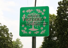 Square street sign text "Welcome to Pettaway Formerly East Broadway Neighborhood 'A Community That Cares'"